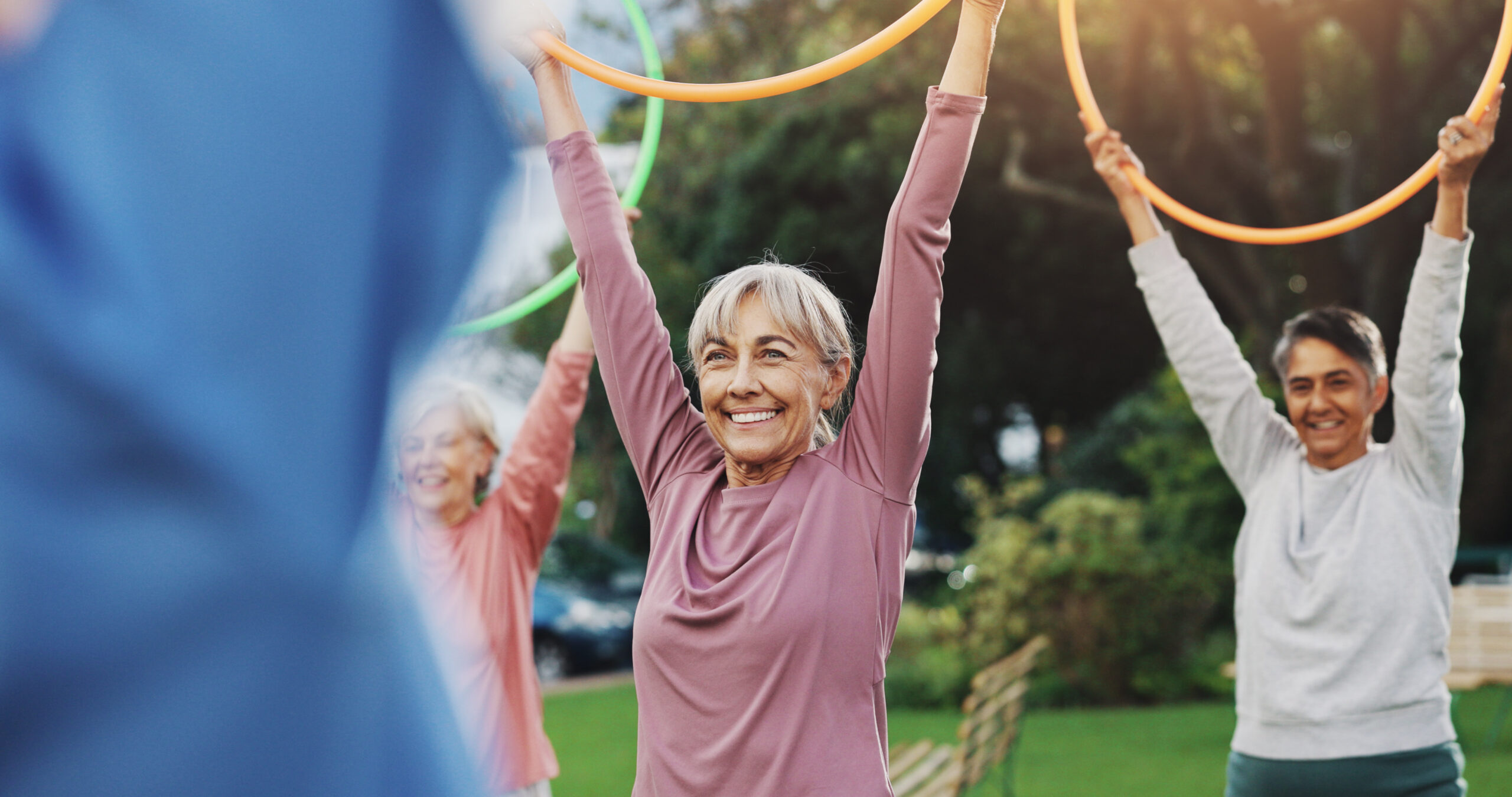 Exercise, senior people and fitness with hula hoop for physical workout, wellness and rehabilitation. Retirement, coach and group of elderly friends for training, wellbeing and stretching with toys